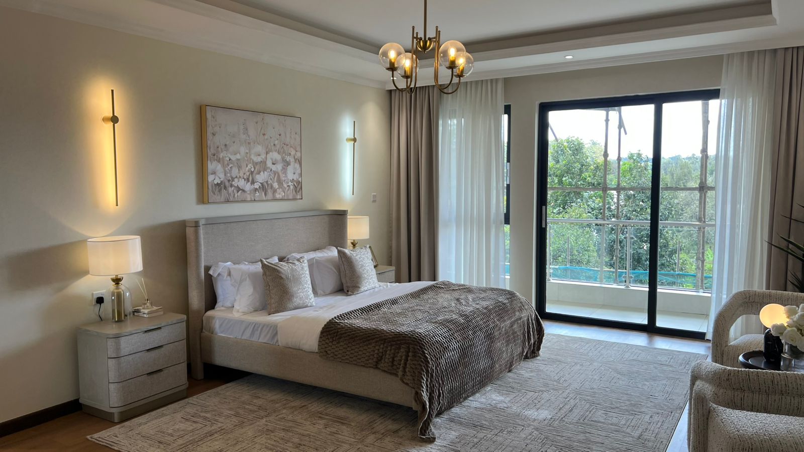 Bedroom at Beacon by Synina, Kileleshwa, with an upholstered bed, chandelier and sliding glass doors to a balcony.