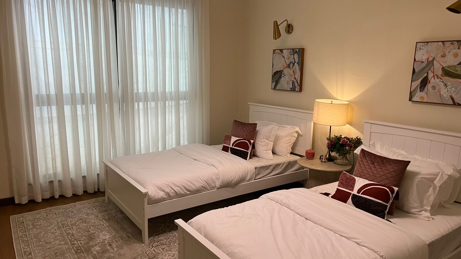 Twin beds with white bedding, burgundy cushions and sheer curtains at Beacon by Synina, Kileleshwa.