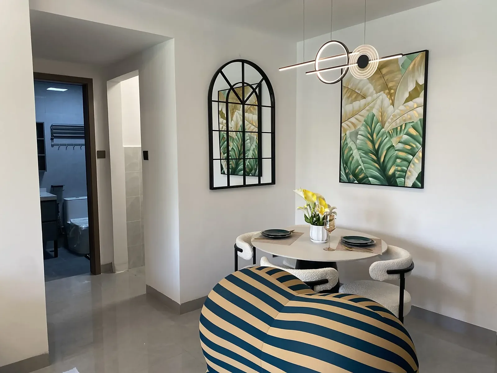 Dining area at Capital Garden, Hurlingham, with a round table, upholstered chairs, arched mirror and pendant light.