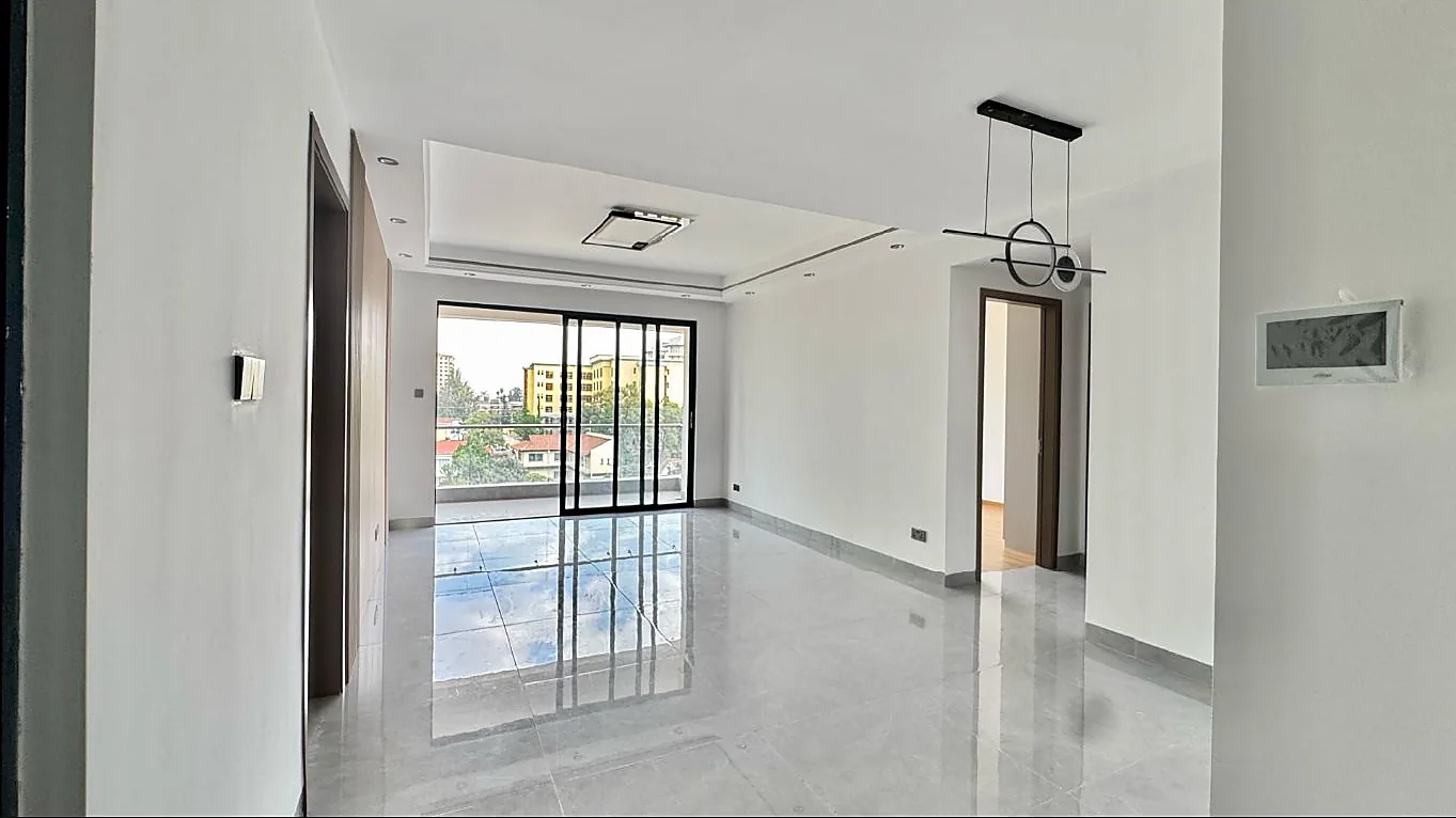 Unfurnished living area at Capital Garden with glossy tiled flooring and sliding glass doors to the balcony.