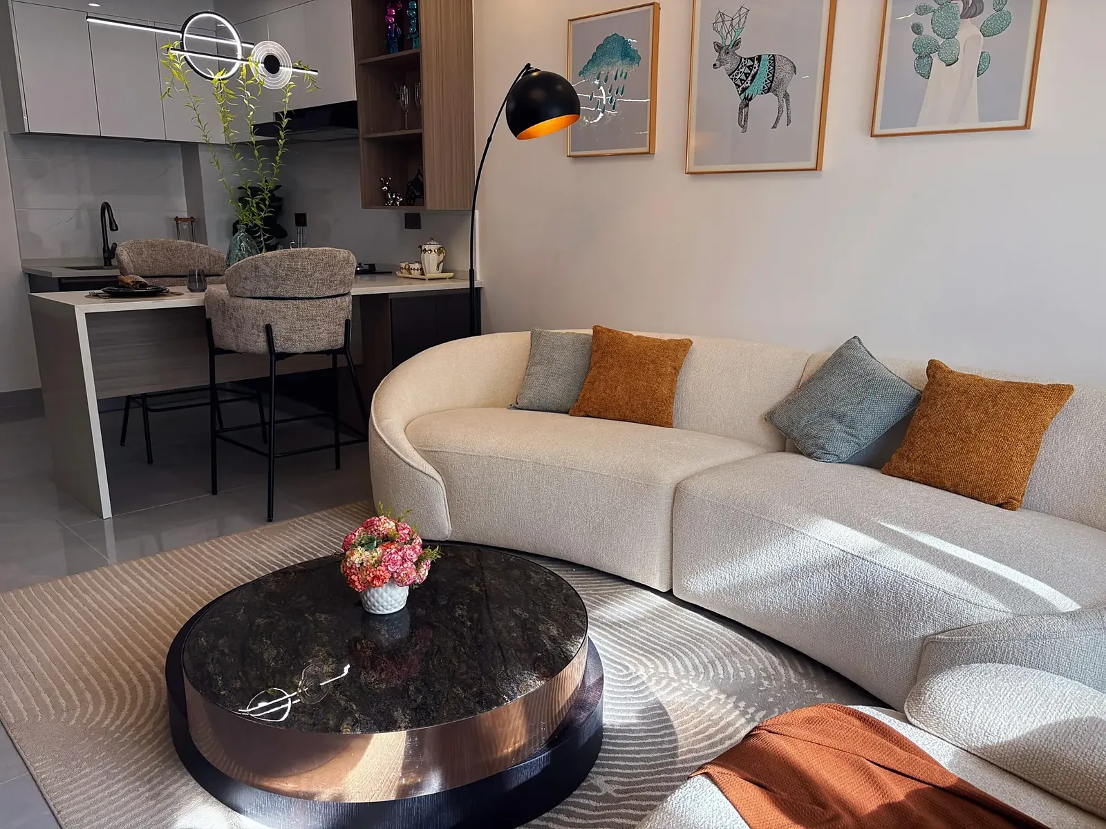 Living area at Capital Garden, Hurlingham, with cream sofa, round coffee table and kitchen breakfast bar.