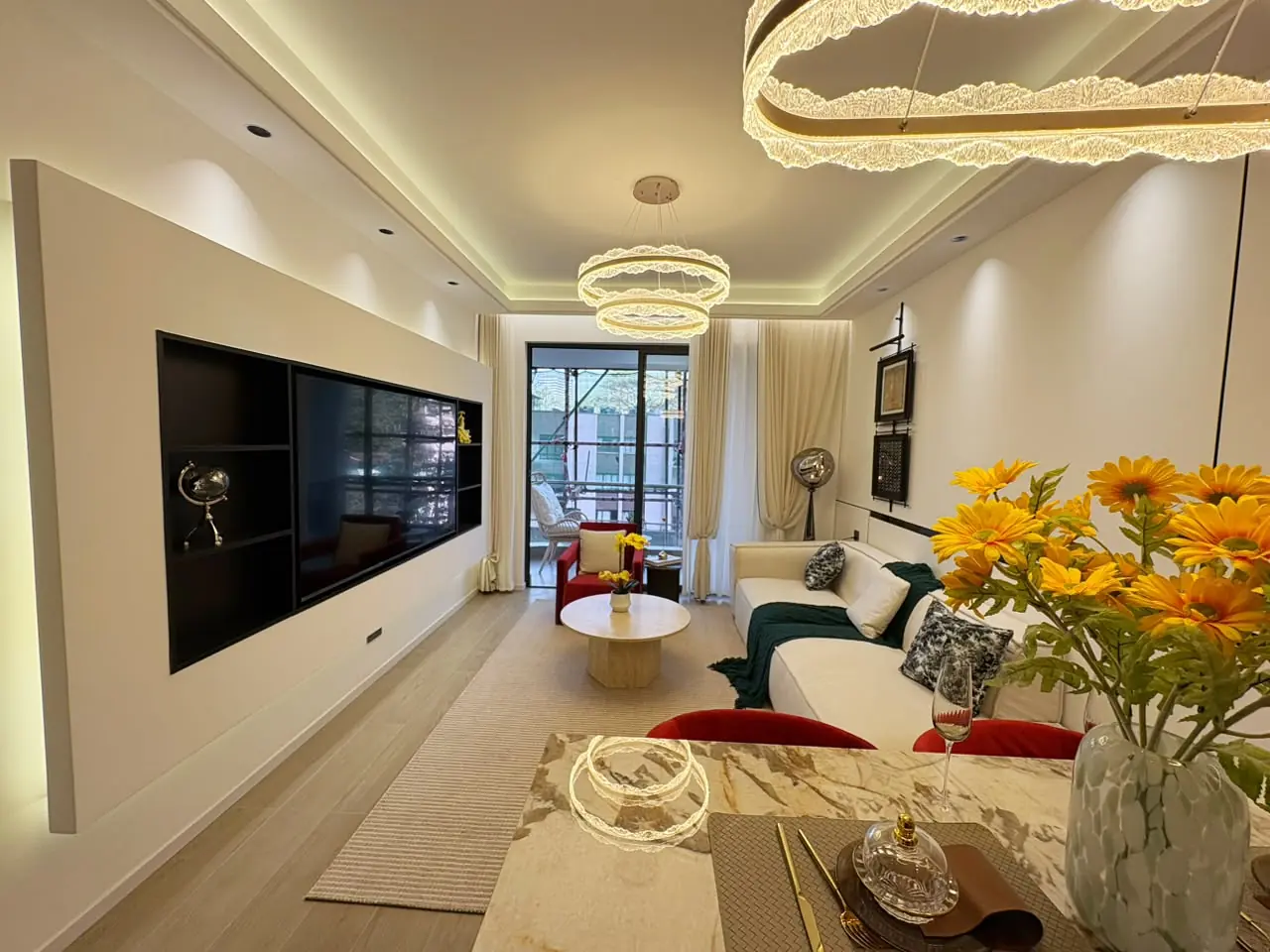 Capital Heights living and dining area with a white sofa, wall-mounted TV and ring pendant lights.