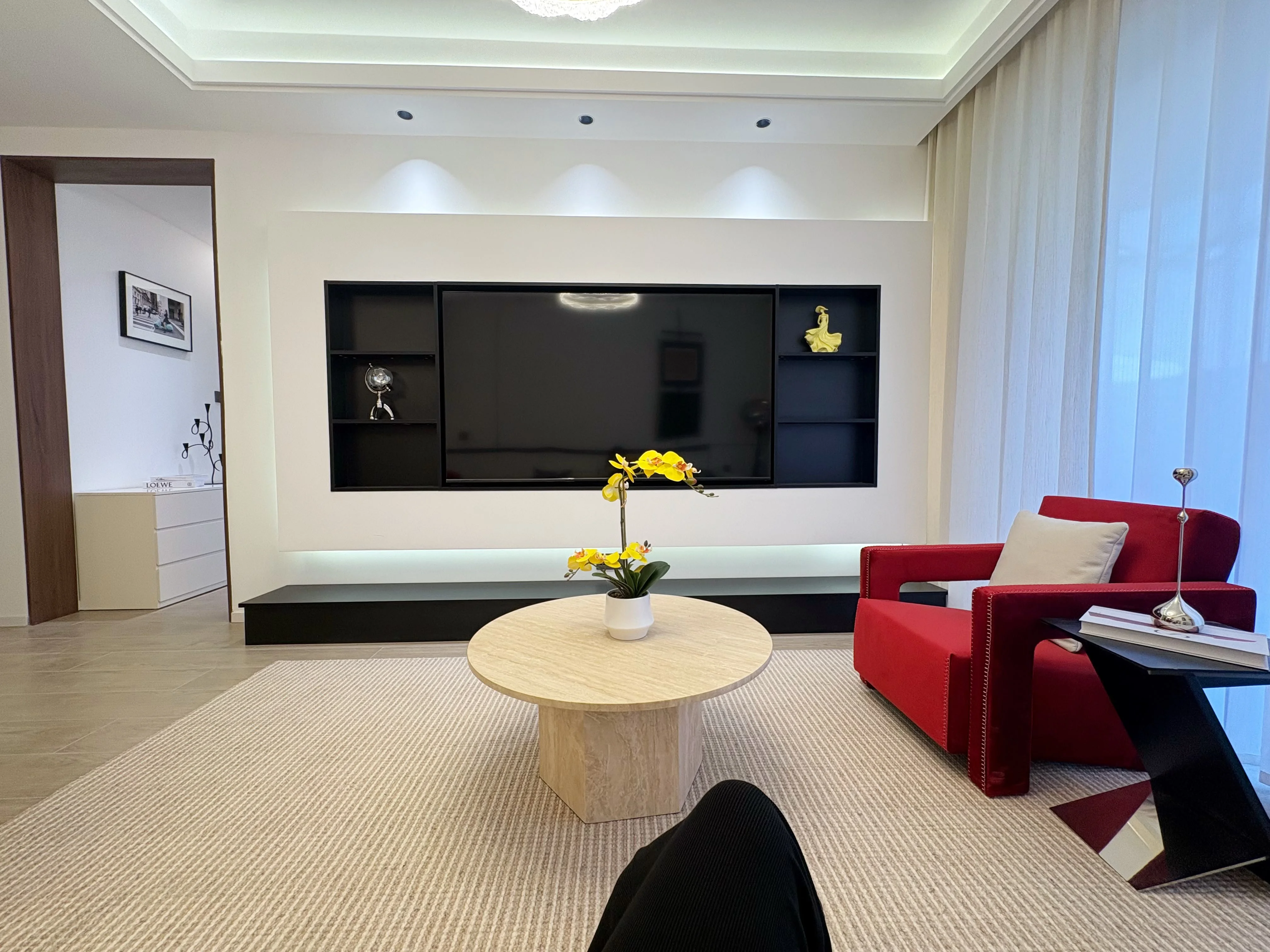 Capital Heights Westlands living room with a TV wall, red armchair and round coffee table.