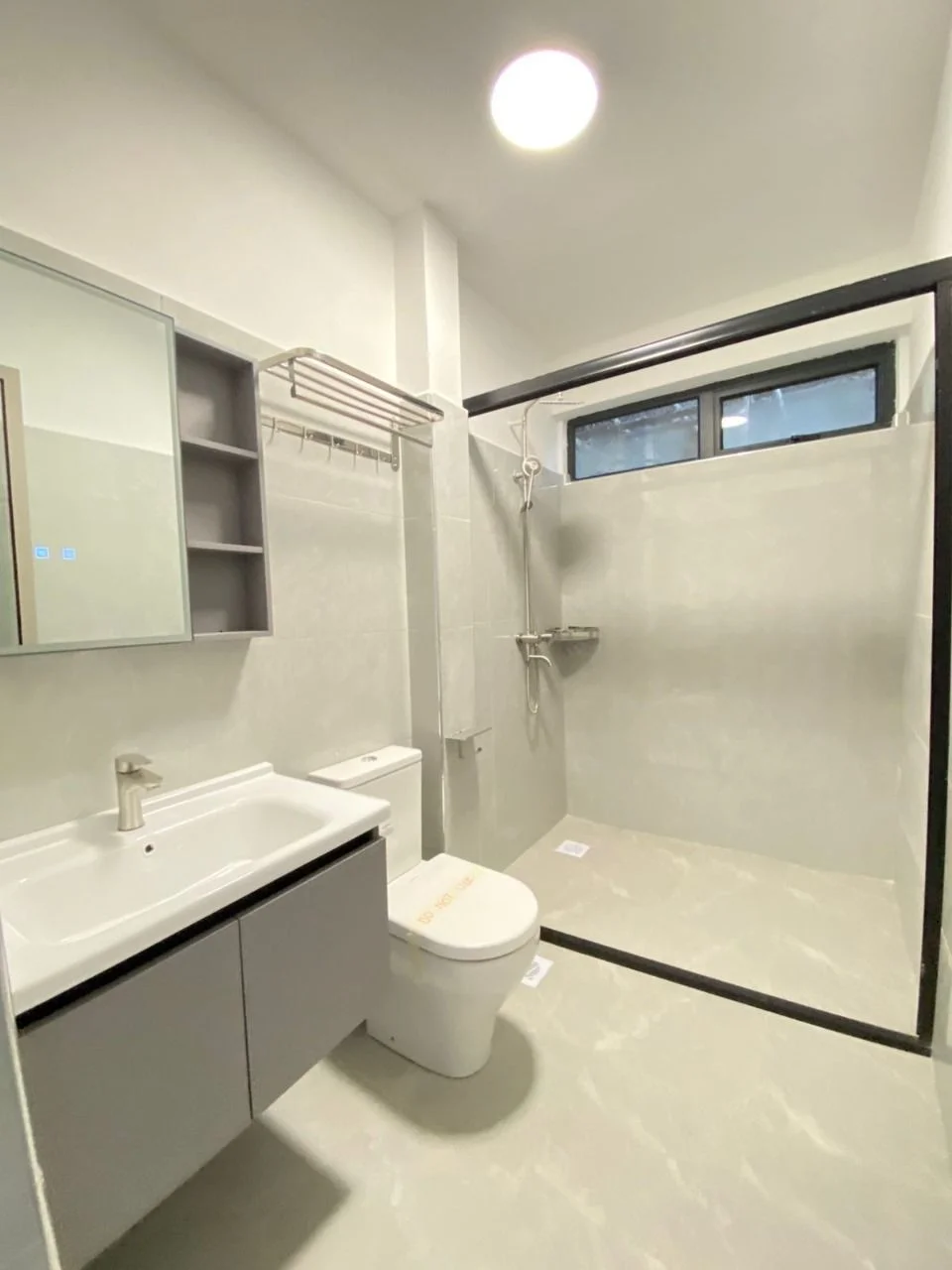Bathroom at Golden Street Residency, Kileleshwa, with grey vanity, toilet and black-framed shower enclosure.