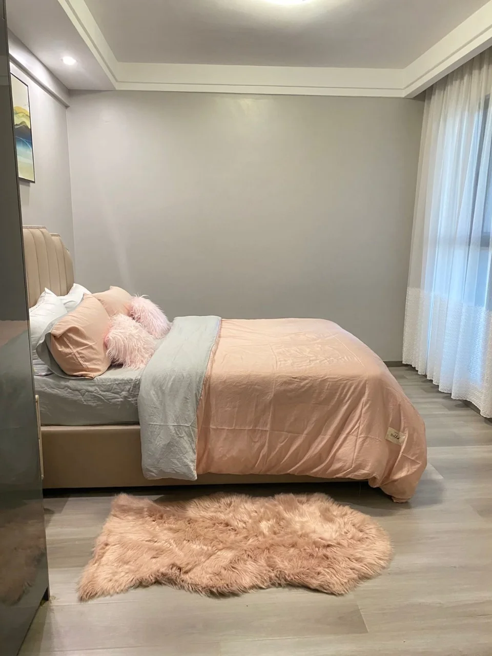 Bedroom with pink bedding, a shag rug and sheer curtains at Golden Street Residency, Kileleshwa.