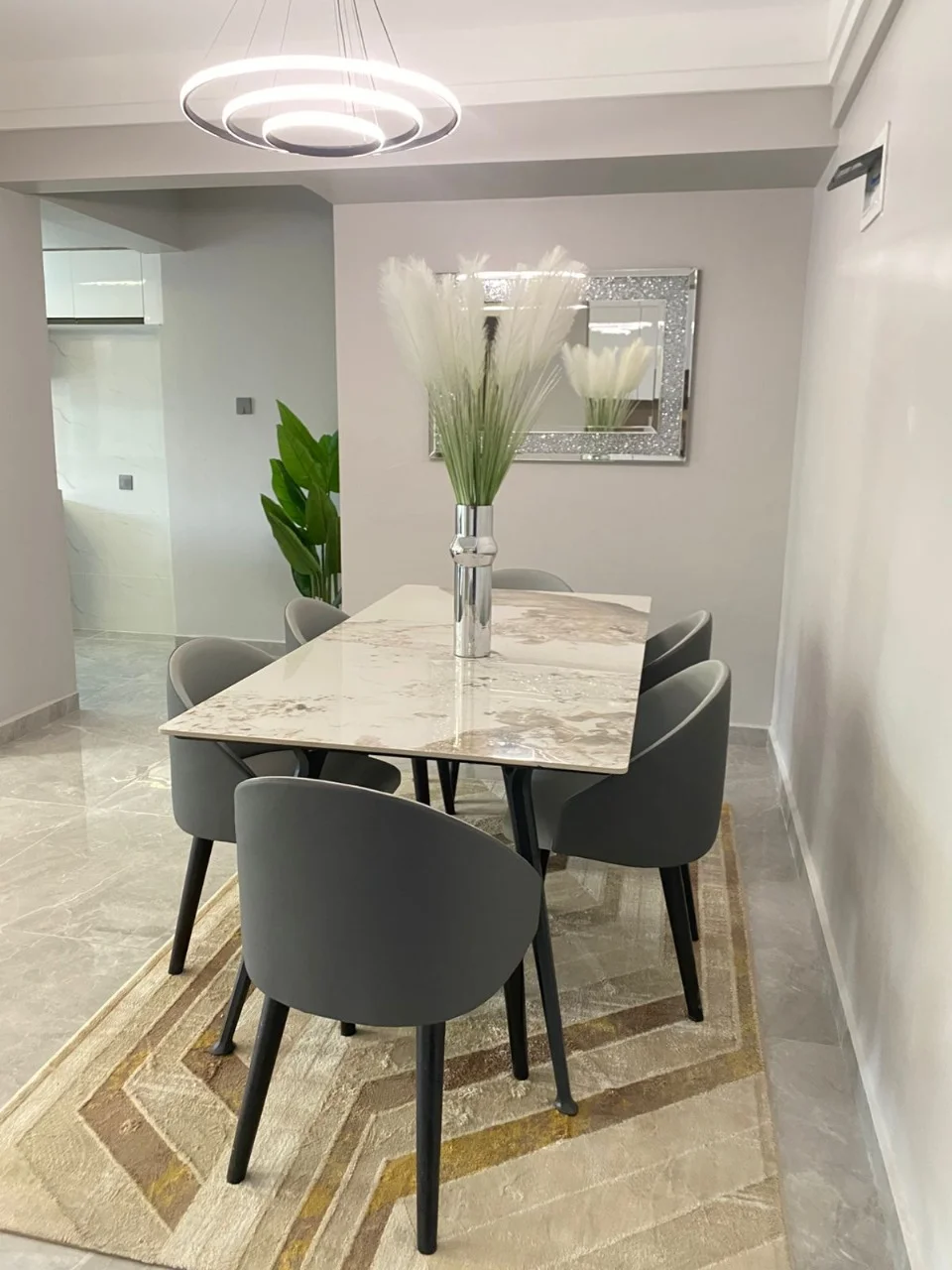 Dining area at Golden Street Residency, Kileleshwa, with grey chairs, a rectangular table and ring pendant lighting.