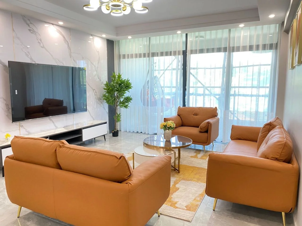 Living room with tan seating, round coffee tables and sheer curtains at Golden Street Residency, Kileleshwa.
