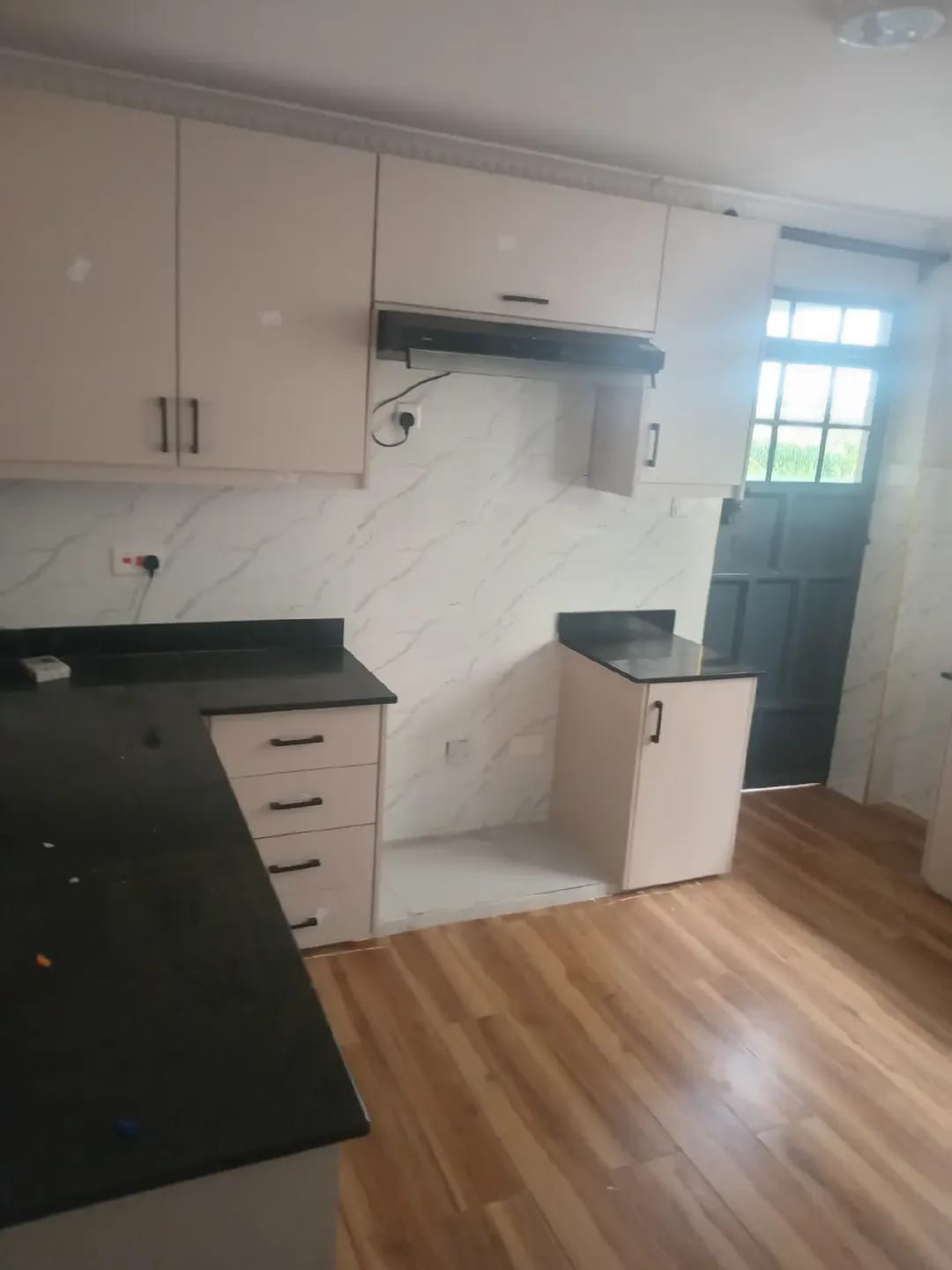 Kitchen in Karen, Kerarapon, with cream cabinets, black countertops and an extractor hood.