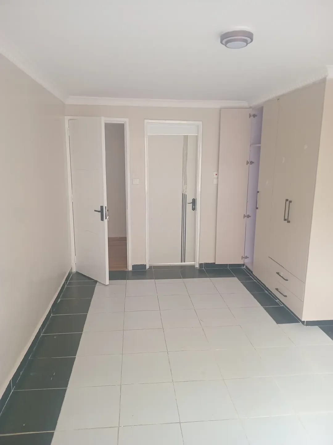 Unfurnished room in Karen, Kerarapon, with built-in wardrobes and light floor tiles bordered by dark tiles.