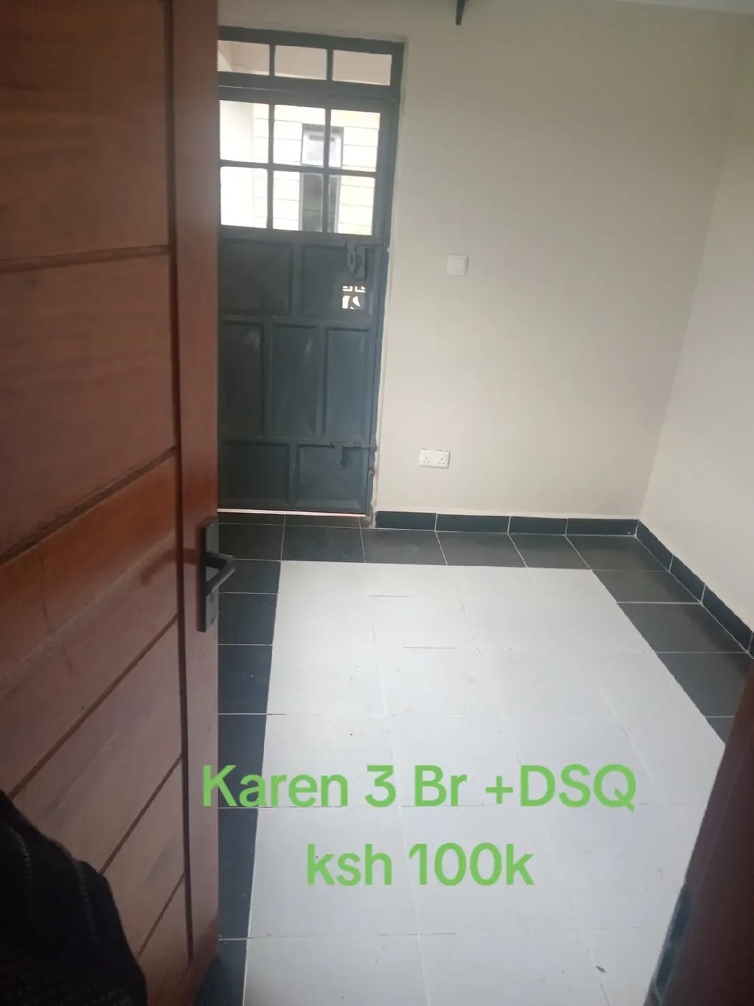 Empty interior with white tiles, dark floor borders and a glazed metal door in Karen, Kerarapon.