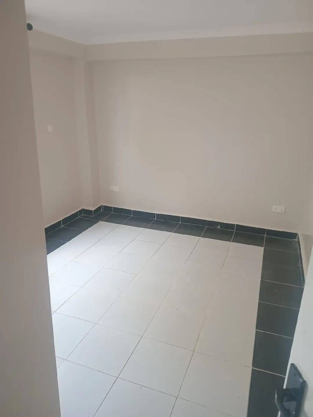 Unfurnished room in Karen, Kerarapon, with beige walls and light floor tiles edged by a dark border.