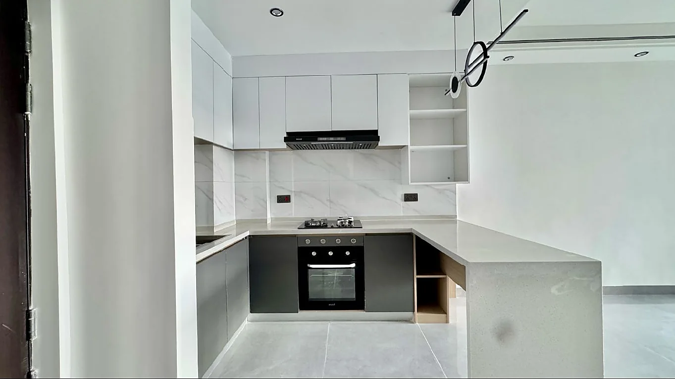 Kilimani apartment kitchen with white and grey cabinets, built-in oven, hob and a peninsula counter.