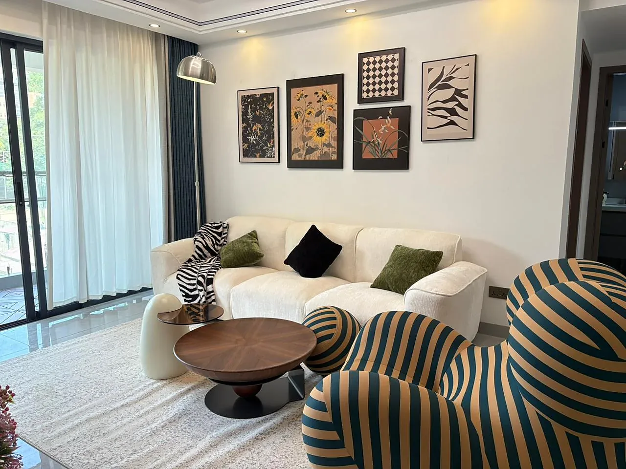 Kilimani apartment living room with a cream sofa, striped armchair, round coffee table and framed wall art.