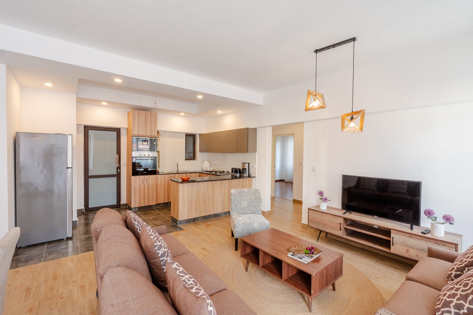 Furnished open-plan living room and kitchen in Kilimani, with sofas, a coffee table and pendant lights.
