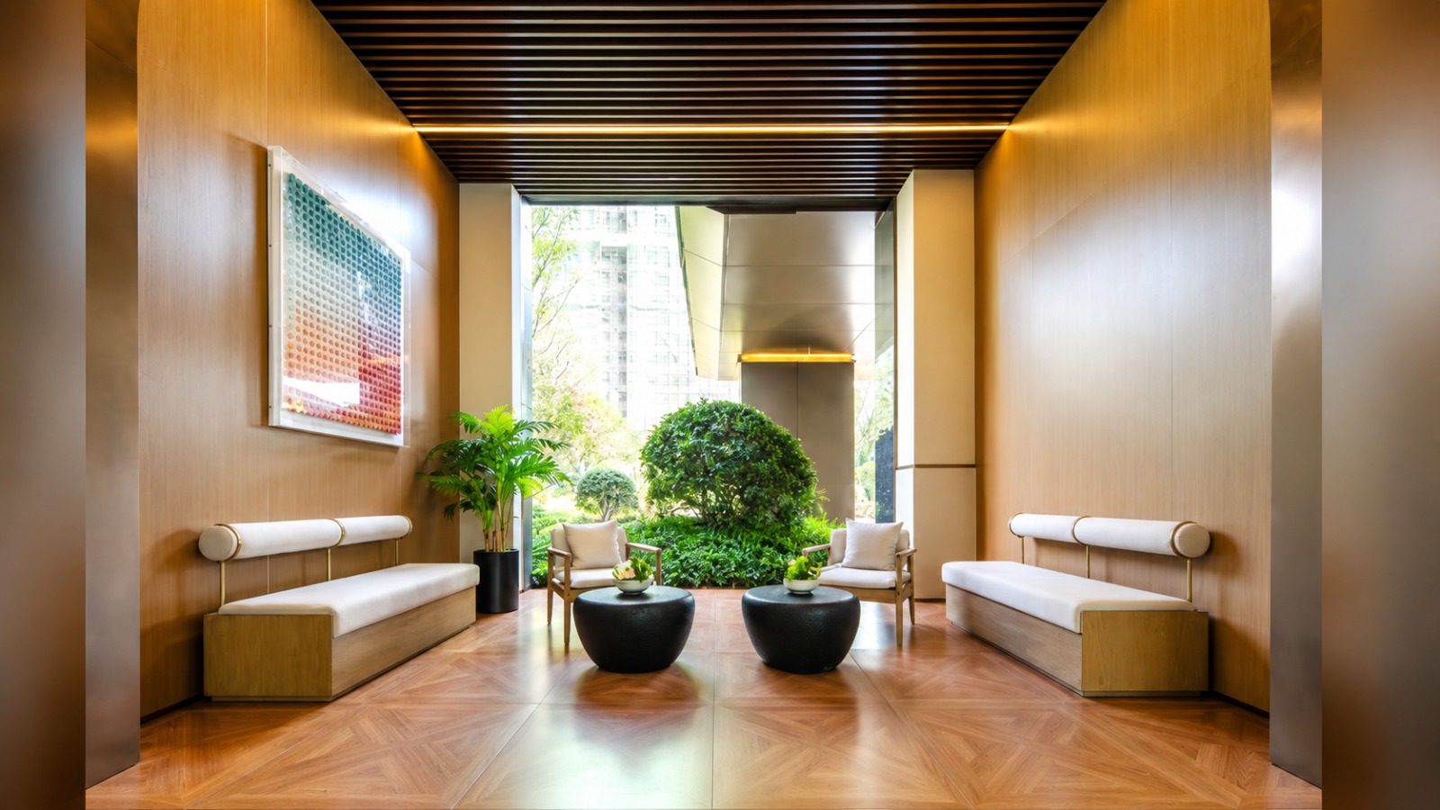 Seating area at Longines Bay, Kilimani, with cushioned benches, armchairs, round black tables and greenery.