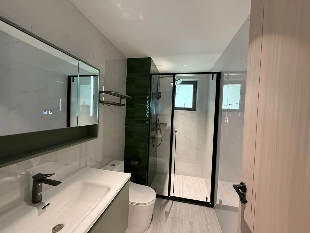 Bathroom at Mara Grove Residence, Syokimau, with a vanity, toilet and black-framed glass shower enclosure.