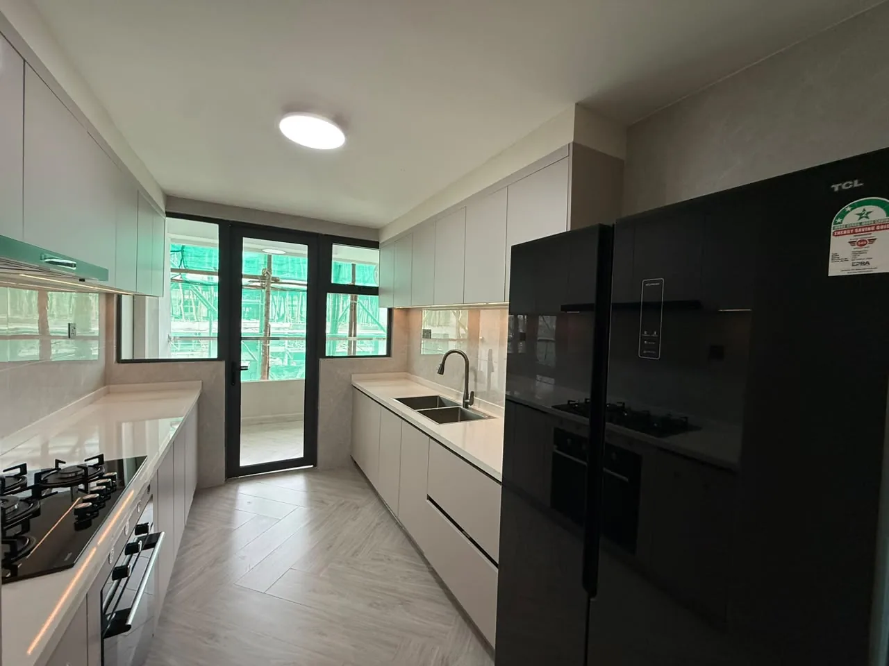 Galley kitchen at Mara Grove Residence, Syokimau, with grey cabinets, double sink, gas hob and black refrigerator.