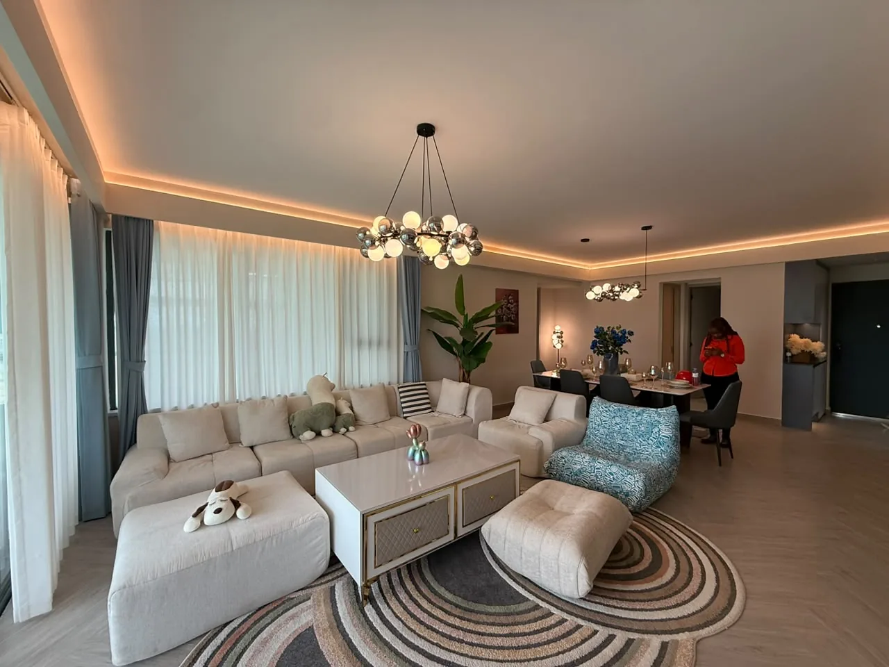 Mara Grove Residence living and dining area with cream seating, a patterned rug and pendant lights.