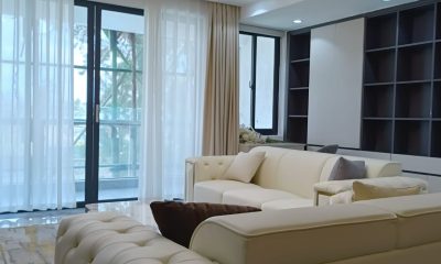 Living room at San Remo Heights, Westlands, with cream sofas, dark shelving and sheer curtains.