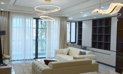 San Remo Heights living room with cream sofas, circular pendant lights and dark built-in shelving.