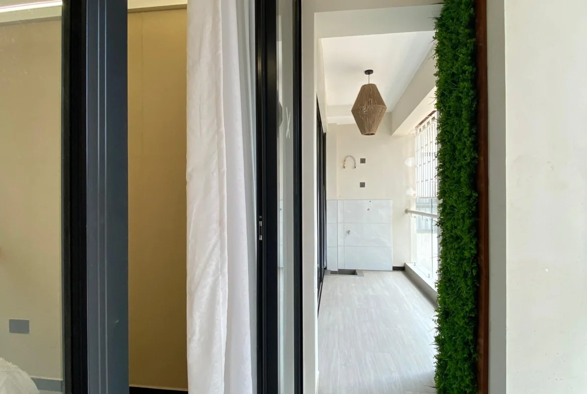 Narrow balcony at Super Westbury, Westlands, with a woven pendant light, glass railing and vertical greenery.