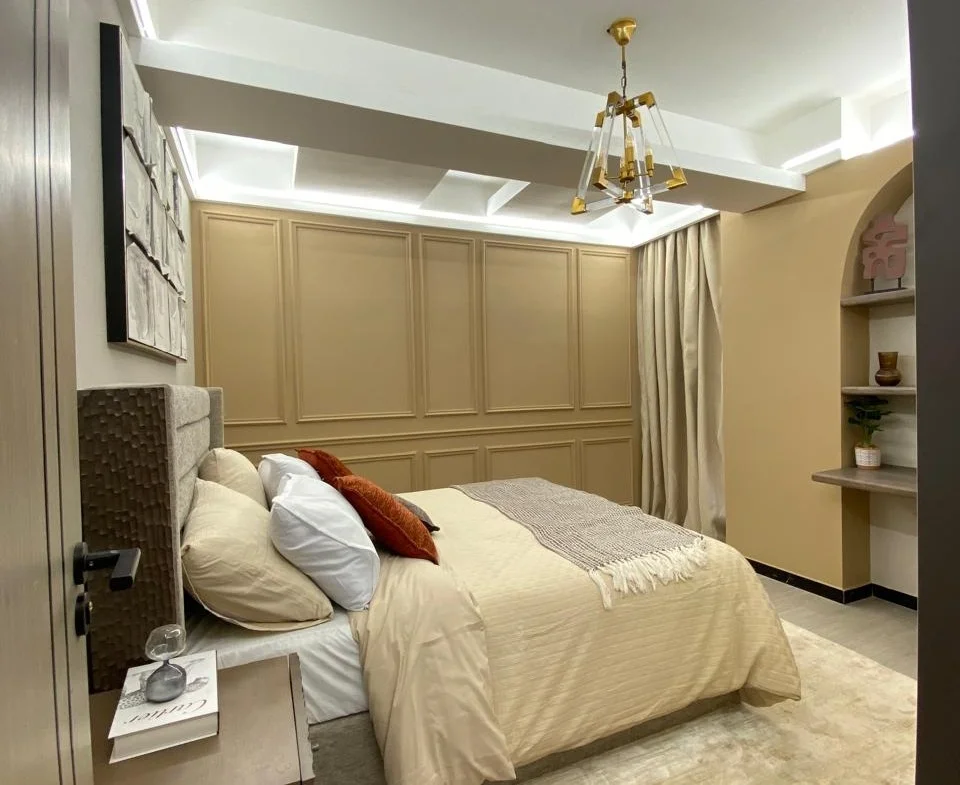 Bedroom at Super Westbury, Westlands, with cream bedding, decorative wall mouldings and a geometric pendant light.