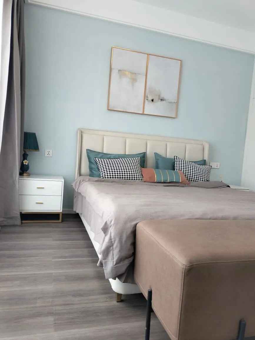 Bedroom at Versailles Garden, Kileleshwa, with an upholstered headboard, patterned cushions and framed artwork above the bed.