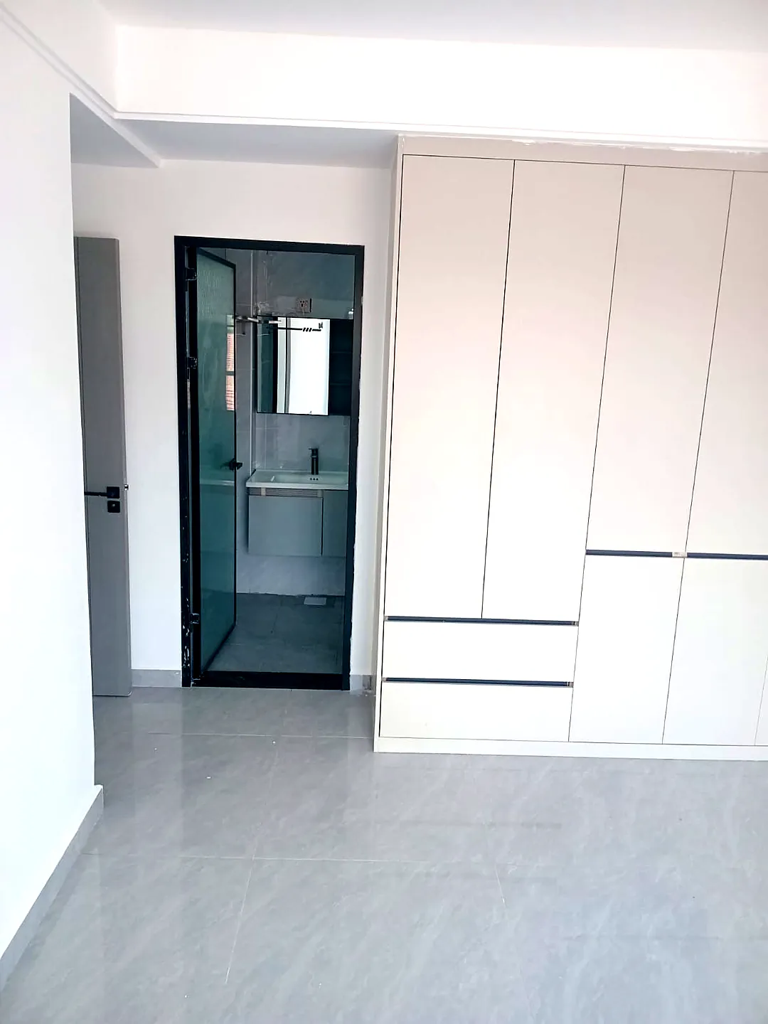 White built-in wardrobe beside a bathroom doorway showing a sink and mirror at Versailles Garden, Kileleshwa.