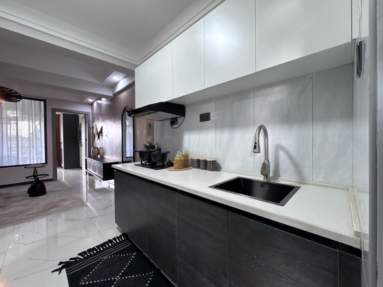 Kilimani apartment kitchen with white upper cabinets, dark lower cabinets, a black sink and hob.